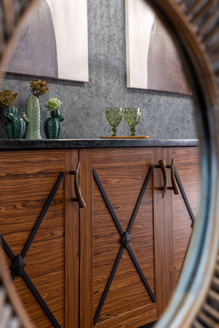 our-experience Through oval shaped hole view of glasses with ornament on tray against vases with decorative plants on table in house