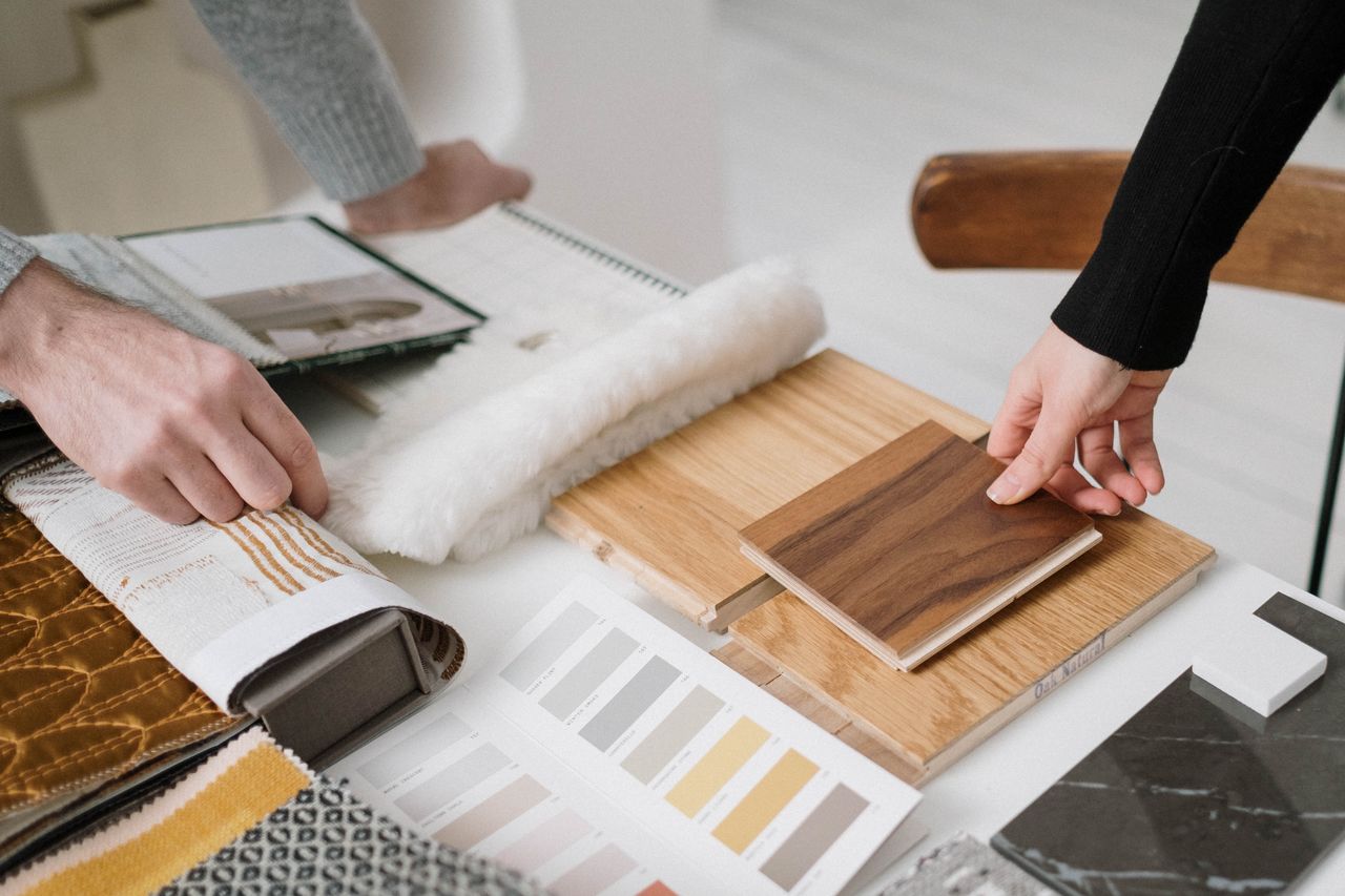 services-01 Hands selecting and comparing textile and wood samples for interior design.